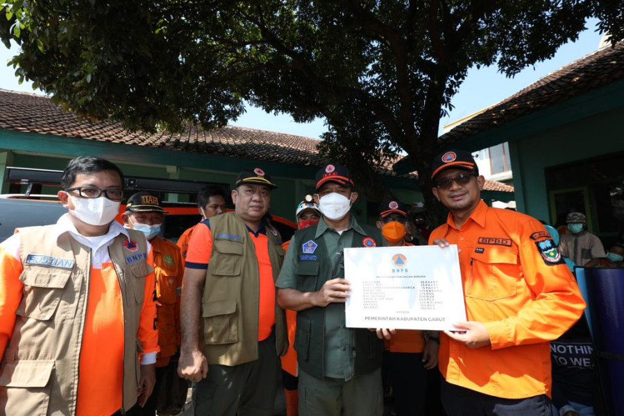 Kepala BNPB Letjen TNI Suharyanto (dua kiri rompi hijau) didampingi Wakil Bupati Garut dr. Helmi Budiman (kanan) menyerahkan bantuan bagi warga terdampak banjir dan tanah longsor di Kamp. Dayeuh Handap, Kel. Kota Kulon, Kec. Garut Kota, Garut, Jawa Barat, Selasa (19/7).